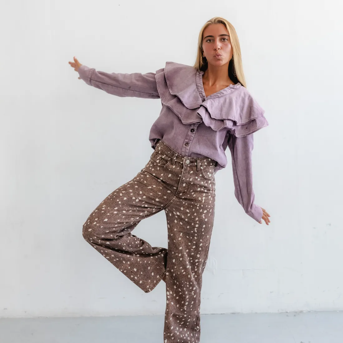 Modelo com camisa lilás de folhos e calças estampadas